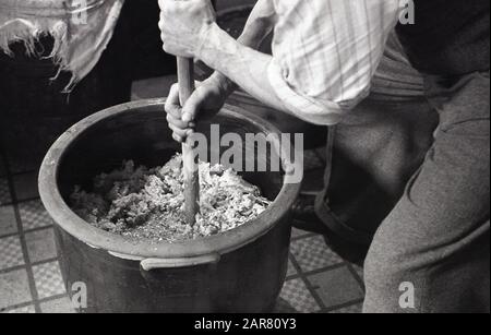 Années 1950, historique, Making mead, un gentleman utilisant un outil de mélange en bois pour décomposer le miel brut cristallisé dans un grand bol en grès, pour faire l'ancienne boisson alcoolisée mead, également connu sous le nom de vin de miel, Angleterre, Royaume-Uni. Banque D'Images