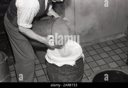 Années 1950, historique, faisant de l'hydromel, un homme versant du liquide chaud d'un récipient en métal dans un tonneau en bois recouvert de lin, en cours de production d'hydromel, l'ancienne boisson alcoolisée, également connue sous le nom de vin de miel, Angleterre, Royaume-Uni. Banque D'Images