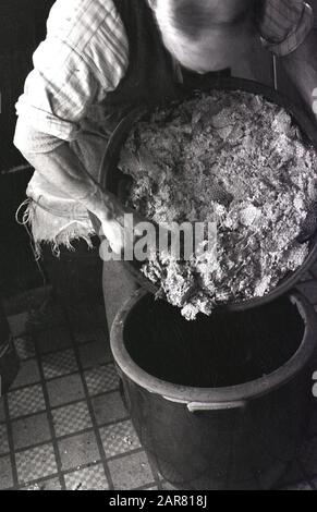 Années 1950, historique, faisant de l'hydromel, un homme mettant des morceaux de miel naturel dans un lourd bol en grès émaillé, en train de produire de l'hydromel, l'ancienne boisson alcoolisée, qui est également connue sous le nom de vin de miel, Angleterre, Royaume-Uni. Banque D'Images