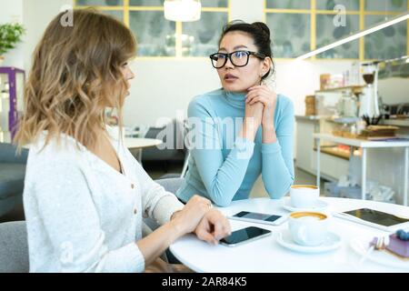 Deux jeunes femmes d'affaires interculturelles en tenue de travail discutant de points de travail Banque D'Images
