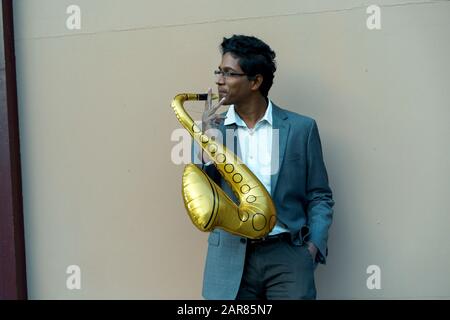 Bel homme drôle avec un tube gonflable couleur or Banque D'Images