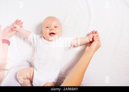 La jeune mère tient un petit garçon de bébé heureux tenant des jambes jouant dans la vue du lit ci-dessus Banque D'Images