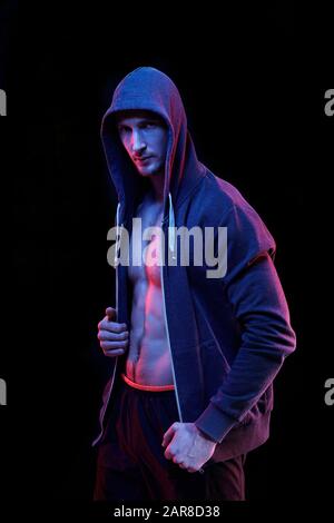 Jeune athlète musculaire masculin dans un sweat à capuche non zippé devant l'appareil photo Banque D'Images