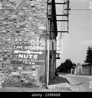 Mémorial du Mardasson, le mémorial de la guerre des États-Unis à Bastogne, Belgique statue de Bastogne; sur le coin de la maison un panneau pointant vers les casernes: Grotte Historique NOIX poste de Comp du gras Mc Auliffe 1944. Annotation : « NUTS (absurdités) se réfère à la réponse donnée par l'unité de thérapie générale américaine McAuliffe à la demande allemande de remise à la bataille de Bastogne en décembre 1944 Date: 1956 lieu: Bastogne, Belgique mots clés: Plaques nominatives, images de rue Banque D'Images