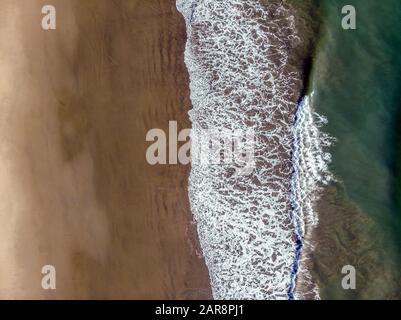 En regardant par-dessus, les vagues se lavant sur la plage de sable. L'eau de mer un gradient naturel vert émeraude de départ jusqu'au sable sec. Banque D'Images