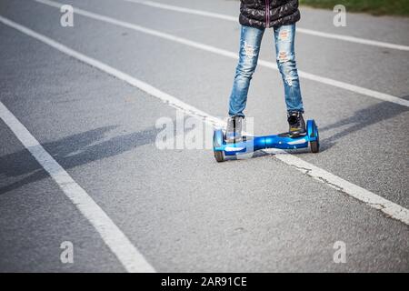 Personne sur le planboard bleu. Conduite à l'aide d'un hyroscooter electriique. Scooter à deux roues auto-équilibré ou scooter à planer. Scooter électrique, scooter gyroscopique, pe Banque D'Images