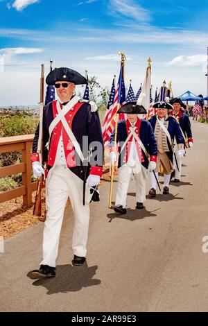 Portant des drapeaux américains et des mousquets historiques, un garde-couleur des uniformes révolutionnaires américains défilés lors d'une célébration du 4 juillet à Newport Beach, Californie. Banque D'Images