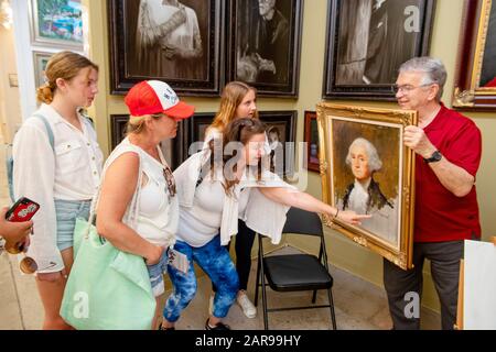 Dans une galerie d'art de Laguna Beach, CA, un artiste affiche sa copie du célèbre portrait de Gilbert Stuart de George Washington, tandis que les visiteurs amusent soulignent la signature de l'artiste sur la photo. Banque D'Images