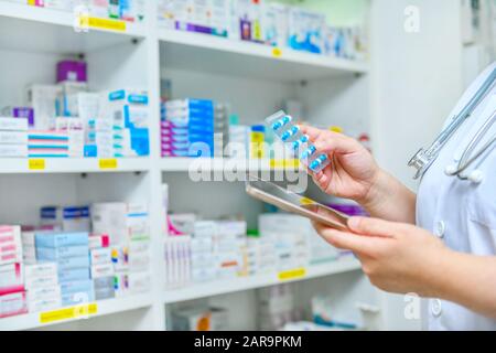 Médecin tenant médicament capsule pack et tablette informatique pour remplir la prescription en pharmacie pharmacie pharmacie pharmacie. Banque D'Images