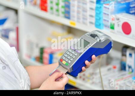 Effectuer des achats, Payer avec une carte de crédit et utiliser un terminal sur de nombreux médicaments en arrière-plan de pharmacie. Banque D'Images