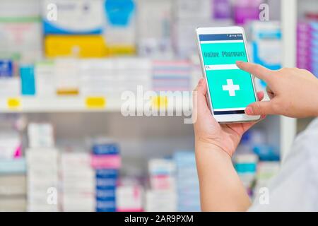 Pharmacien utilisant le smartphone mobile pour la barre de recherche sur l'affichage dans pharmacie rayons de pharmacie arrière-plan.concept médical en ligne. Banque D'Images