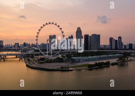 Coucher de soleil sur le front de mer de Singapour, près de Marina Bay, avec la célèbre roue Ferris à Singapour, en Asie du Sud-est Banque D'Images