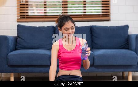 La jeune femme asiatique prend un repos après l'entraînement et boire de l'eau après l'entraînement dans le salon Banque D'Images