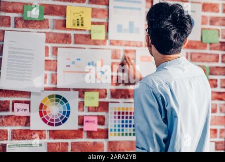 Directeur de la création homme asiatique à la designer graphique et trouver des données à l'idée de bureaux modernes à brickwall.brainstroming idées créatives concpet Banque D'Images