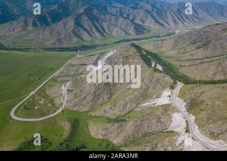 Vue aérienne de Serpentine Road Parmi les collines vertes du col de Chike-Taman dans les montagnes de l'Altaï. Route asphaltée traversant la falaise. Banque D'Images