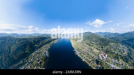 Vue aérienne de l'embouchure dans le lac Teletskoye large dans les montagnes de l'Altaï par l'eau, bleu ciel avec des nuages blancs, vert des arbres sur les pentes de l'un des roches Banque D'Images