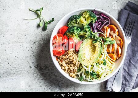 Salade végétalienne de Bouddha avec quinoa, avocat, brocoli, patate douce et vinaigrette tahini, fond gris. Banque D'Images