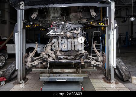 Remplacement du moteur usagé sur une table montée sous une voiture relevée sur le pont élévateur pour l'installation après une panne et une réparation dans un atelier de véhicule comme garantie Banque D'Images