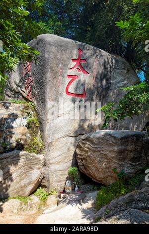 Des personnages rouges sculptés sur une grande roche avec un petit autel en dessous. Temple A-Ma, Macao, Chine. Banque D'Images