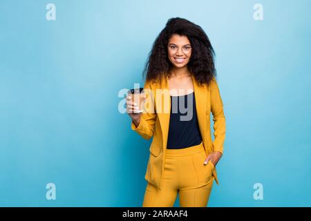 Photo d'une jolie dame d'affaires chic et sombre qui tient chaud à emporter café boissons entreprise dîner pause vêtements spécifications jaune costume blazer pantalon Banque D'Images