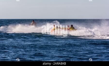 amis touristes se moquant à la conduite sur le tube d'eau avec un scooter sur les vagues de la mer à grande vitesse pendant les vacances d'été Banque D'Images