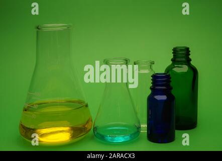 Assortiment de verrerie de laboratoire colorées sur un fond vert dans une image conceptuelle Banque D'Images