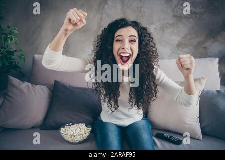 Gros plan portrait de sa belle jolie charmante charmante gaie gaie gaie heureuse excitée fille à poil ondulé assise sur divan célébrant la victoire ayant du plaisir Banque D'Images