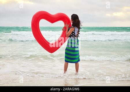 Boracay, Province d'Aklan, Philippines - Le 3 décembre 2019 : Une jeune femme chinoise tient un cœur rouge de l'air en forme de joint torique au niveau de la plage blanche vide Banque D'Images