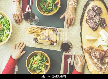 Vue imprenable sur les grands amis qui mangent de la salade, du salami, du fromage et du jambon italien - les personnes âgées dégustant du vin rouge pour dîner au restaurant - Focus on up woman rig Banque D'Images