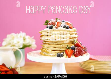 Shrove Pancake Mardi, dernier jour avant Carême, pile de crêpes gâteau préparé avec des couches de crème fouettée et des baies fraîches contre le dos rose moderne Banque D'Images