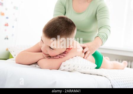 Kids concept massage arrière-plan. Jeune femme massothérapeute donnant un garçon de 6 ans massage dos. La thérapie physique. Banque D'Images