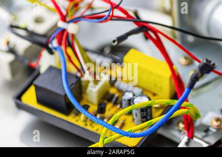 Carte d'alimentation pour un appareil électrique. Câbles électriques multicolores, condenseur. Concept de réparation d'équipement. Mise au point sélective. Gros plan. Banque D'Images