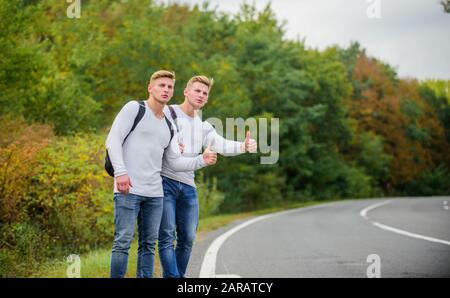 Voyageurs en route. Des amis qui voyagent avec des hitchhikers. Geste de randonnée. Commencez une grande aventure dans votre vie avec la randonnée pédestre. Compagnie amis voyageurs qui déchire à la route nature fond. Banque D'Images