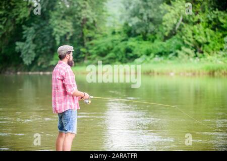 ne regardez pas en arrière. les pêcheurs expérimentés dans l'eau. les pêcheurs montrent la technique de pêche utiliser la tige. l'homme capture le poisson. l'homme mûr la pêche à la mouche. activité sportive et passe-temps. Pêche à la mouche réussie. Week-end d'été. Banque D'Images