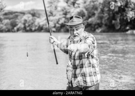 Pêcheur avec canne à pêche. Activité et passe-temps. Lac d'eau douce de la rivière étang de pêche. Il n'est pas le sport, c'est l'obsession. Homme barbu Senior la capture de poissons. Homme mûr la pêche. Ancien pêcheur barbu. Banque D'Images