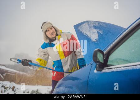 Homme avec crochets de corde de remorquage près de la voiture remorquée Banque D'Images