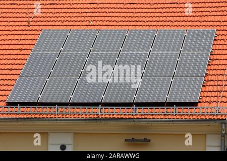 Vue latérale du groupe de dix-huit panneaux solaires neufs montés sur le dessus du bâtiment rénové de bureau nouveau toit entouré d'une petite clôture de neige Banque D'Images
