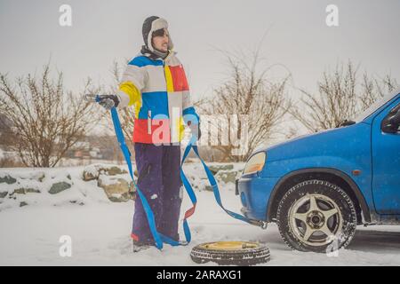 Homme avec crochets de corde de remorquage près de la voiture remorquée Banque D'Images