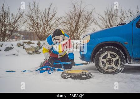 Homme avec crochets de corde de remorquage près de la voiture remorquée Banque D'Images