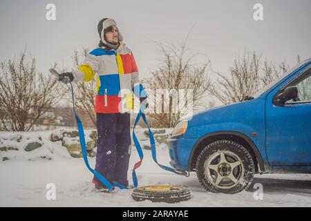 Homme avec crochets de corde de remorquage près de la voiture remorquée Banque D'Images