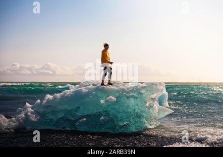 Touriste debout sur un iceberg à la plage de Diamond, Islande Banque D'Images