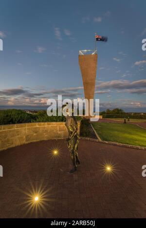 Statue en bronze d'une femme, en soirée, tenant son chapeau dans la brise de la mer surplombant le port de Geraldton sur le site commémoratif du HMAS Sydney 11. Banque D'Images