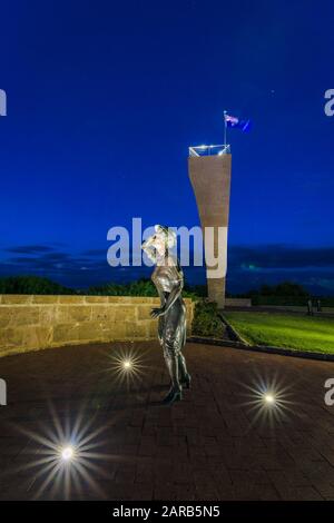 Statue en bronze d'une femme, en soirée, tenant son chapeau dans la brise de la mer surplombant le port de Geraldton sur le site commémoratif du HMAS Sydney 11. Banque D'Images