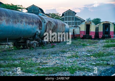 Anciens wagons et voitures devant les hangars à moteur de l'ère coloniale française qui abritent encore un certain nombre de vieilles locomotives à vapeur, Phnom Penh, Cambodge Banque D'Images