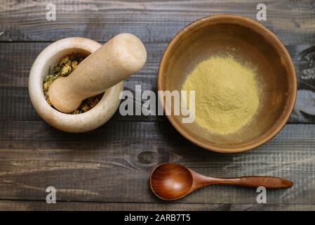 Mortier de marbre avec camomille séchée pour cosmétiques naturels. Bol en argile avec poudre jaune ou argile et fleurs sur fond en bois. Pose plate. Banque D'Images