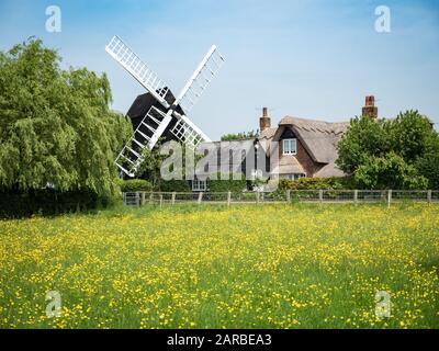 Un ancien moulin à vent anglais traditionnel et un cottage de ferme nichés dans la campagne anglaise du printemps. Cambridgeshire, Royaume-Uni. Banque D'Images