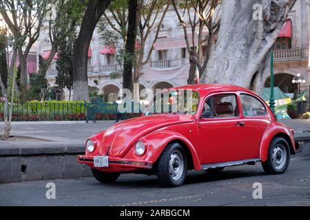 Voiture rouge classique Volkswagen Codendroctone garée sur le côté de la place de la ville dans le centre de Puebla, au Mexique Banque D'Images