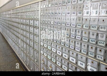 Grand mur de casiers gris de poste de bureau de bureaux de poste de différentes tailles en perspective sélective Banque D'Images