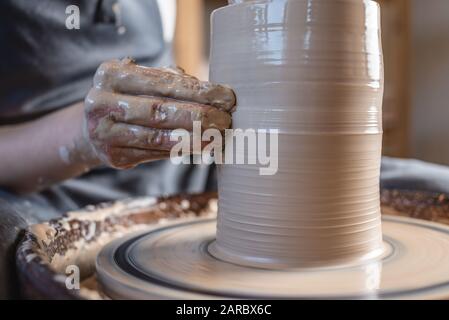 Femme potter travaillant sur une roue de Potter faisant un vase. Maître formant l'argile avec ses mains créant la verseuse dans un atelier. Gros plan Banque D'Images