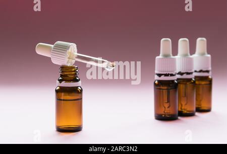 cosmologie, bouteilles en verre avec pipettes et cosmétiques sur fond rose Banque D'Images